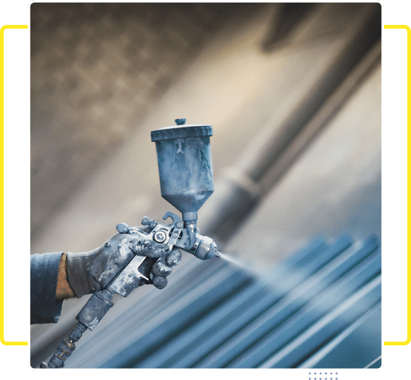 Worker spray painting metal surface with protective gloves on.