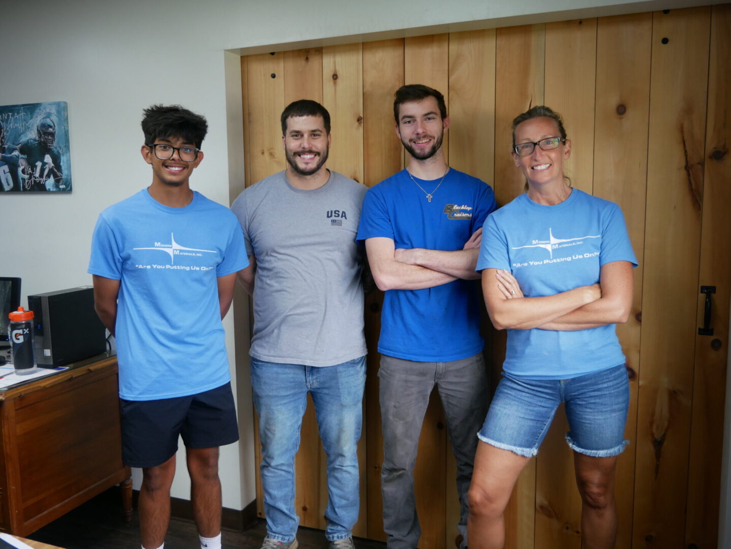 Four men standing indoors, smiling and posing for a photo.