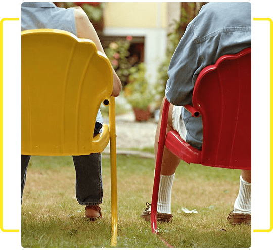 Two people sitting on colorful chairs outdoors in a garden.