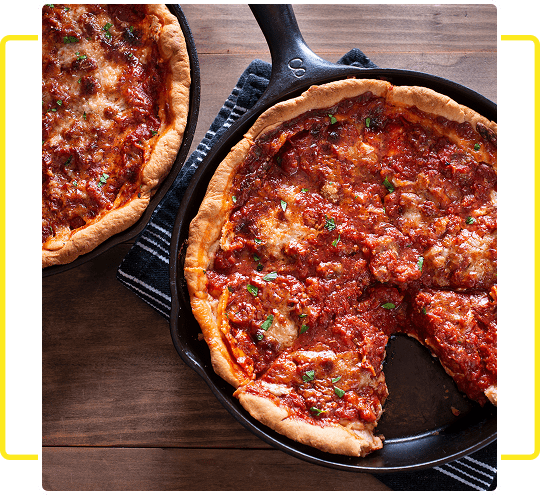 Deep-dish pepperoni pizza in a skillet with one slice removed.