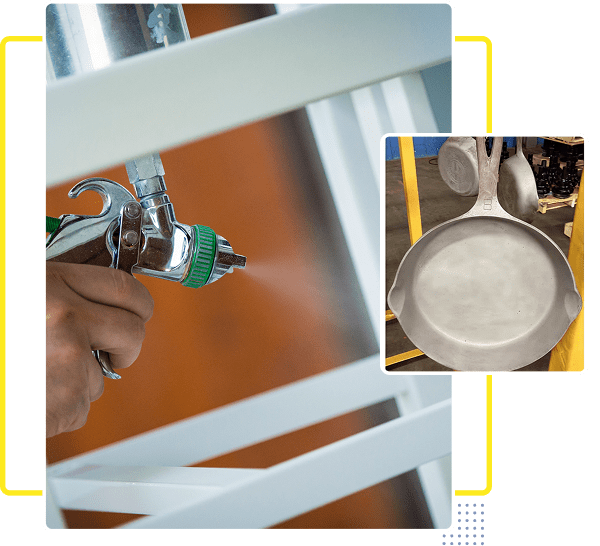 A person spray painting a white metal object with a pan in the corner.
