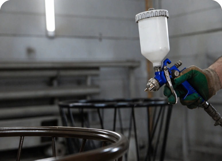 Spray painting metal furniture in an industrial workshop.